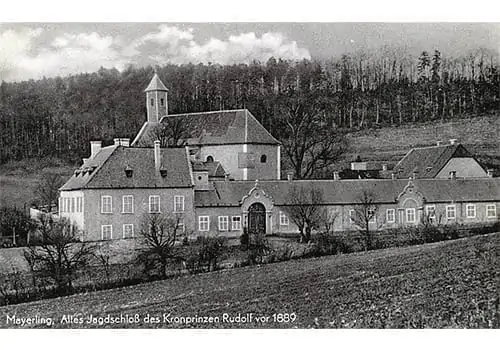Historisches Schwarz-Weiß-Foto eines großen Anwesens mit mehreren zusammenhängenden Gebäuden und einem Kirchturm inmitten eines bewaldeten Hügels; bezeichnet als Meyerling, das ehemalige Jagdschloss von Kronprinz Rudolf vor 1889.
