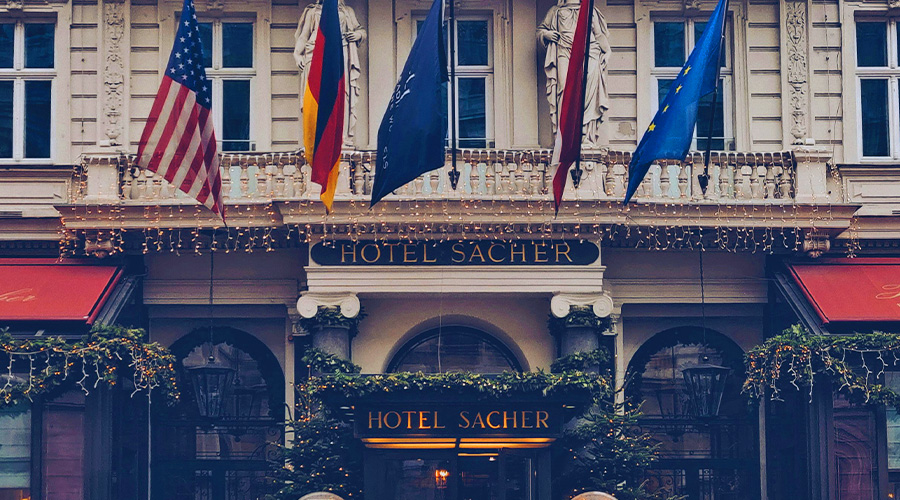 萨克酒店的入口处装饰着花环和童话灯。入口上方悬挂着多面旗帜,包括美国、德国、奥地利和欧盟的旗帜。