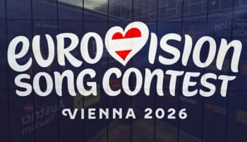 Logo of the Eurovision Song Contest with the word Eurovision in the shape of a heart with the Austrian flag as the letter v. Below it is Vienna 2026 on a dark blue background.