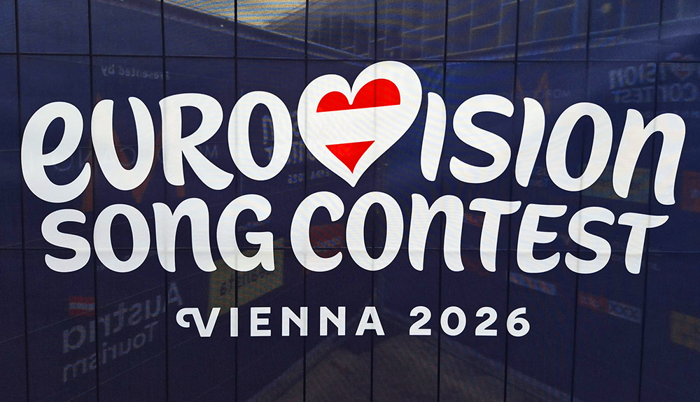 Logotipo del Festival de Eurovisión con la palabra Eurovisión en forma de corazón y la bandera austriaca como letra v. Debajo aparece Viena 2026 sobre fondo azul oscuro.